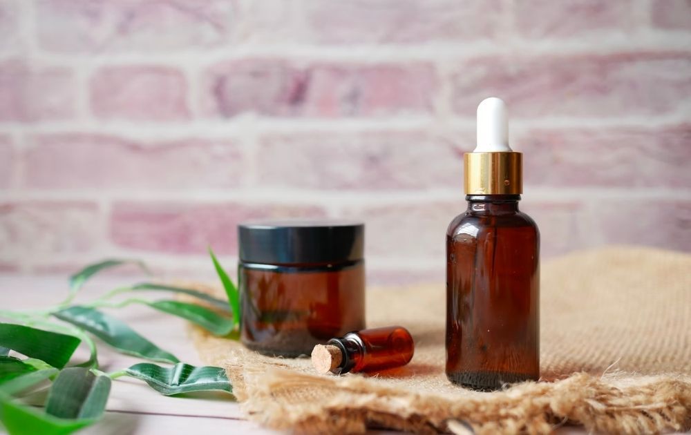 A small jar and a dropper bottle of essential oil