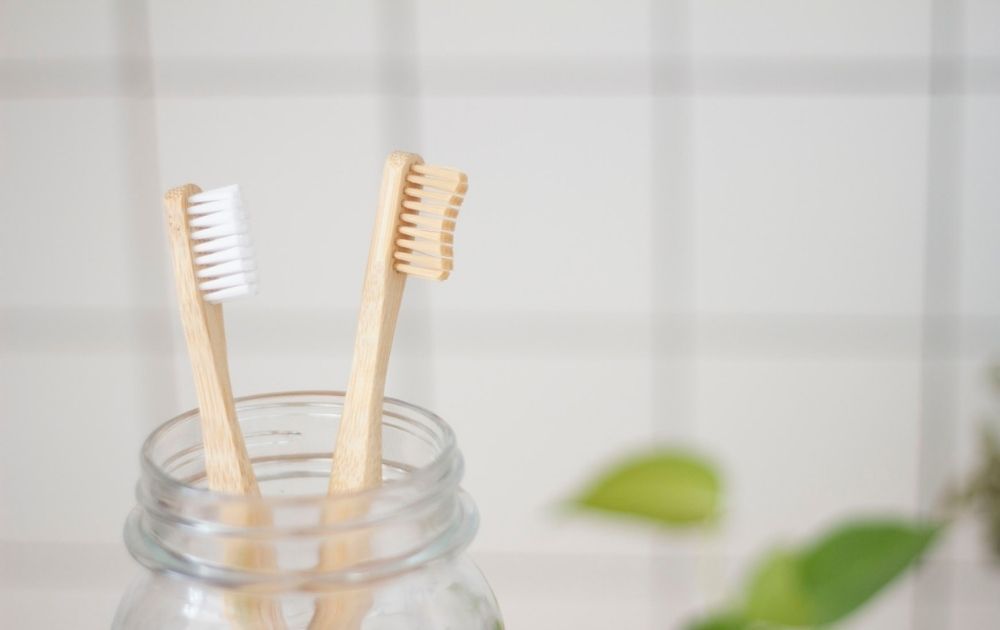 Two bamboo toothbrushes in a glass jar